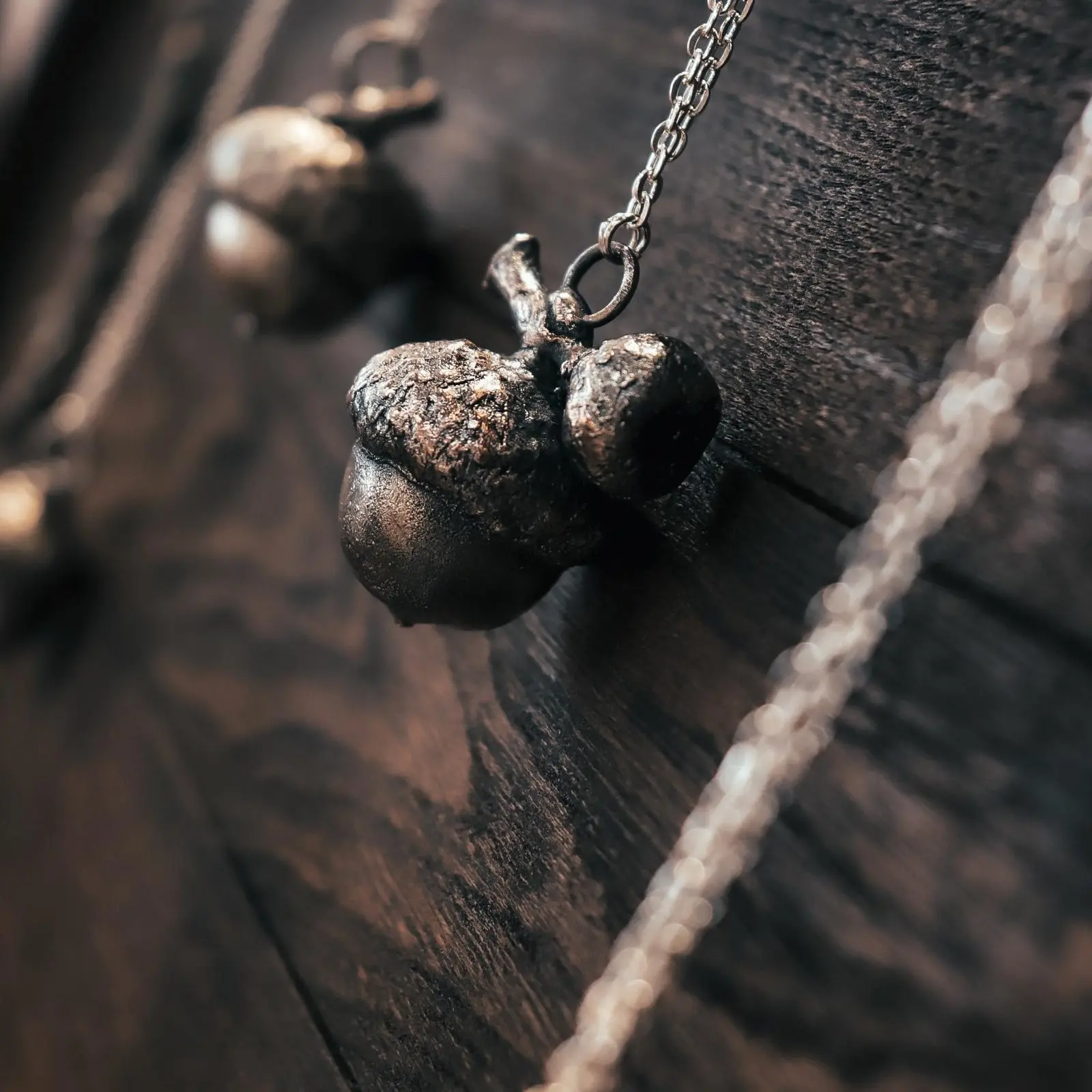 Denise: Eichelkette verkupfert, organischer Schmuck verkupfert, galvanisierte Eicheln an einer Kette vor Holzplatte